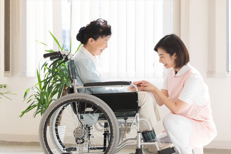車椅子の女性の手を握る介護士